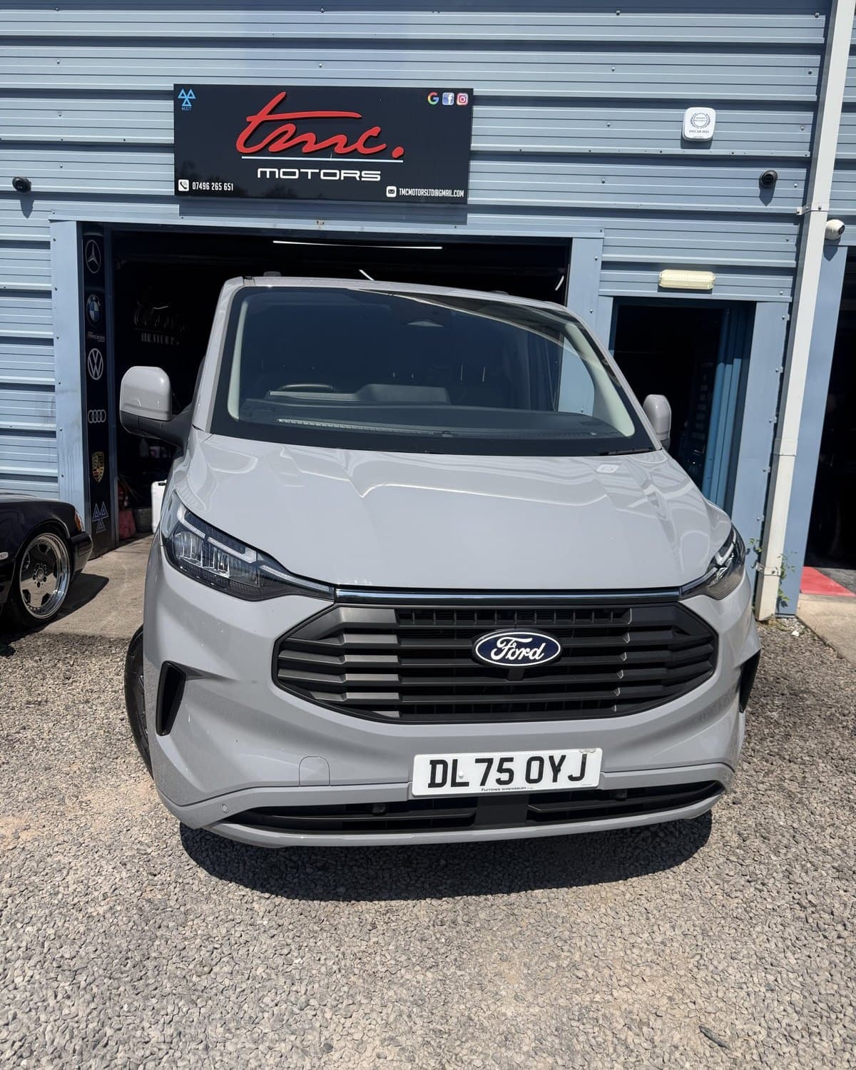A silver Ford Transit Custom van outside the Team Mercedes Cardiff workshop shutter