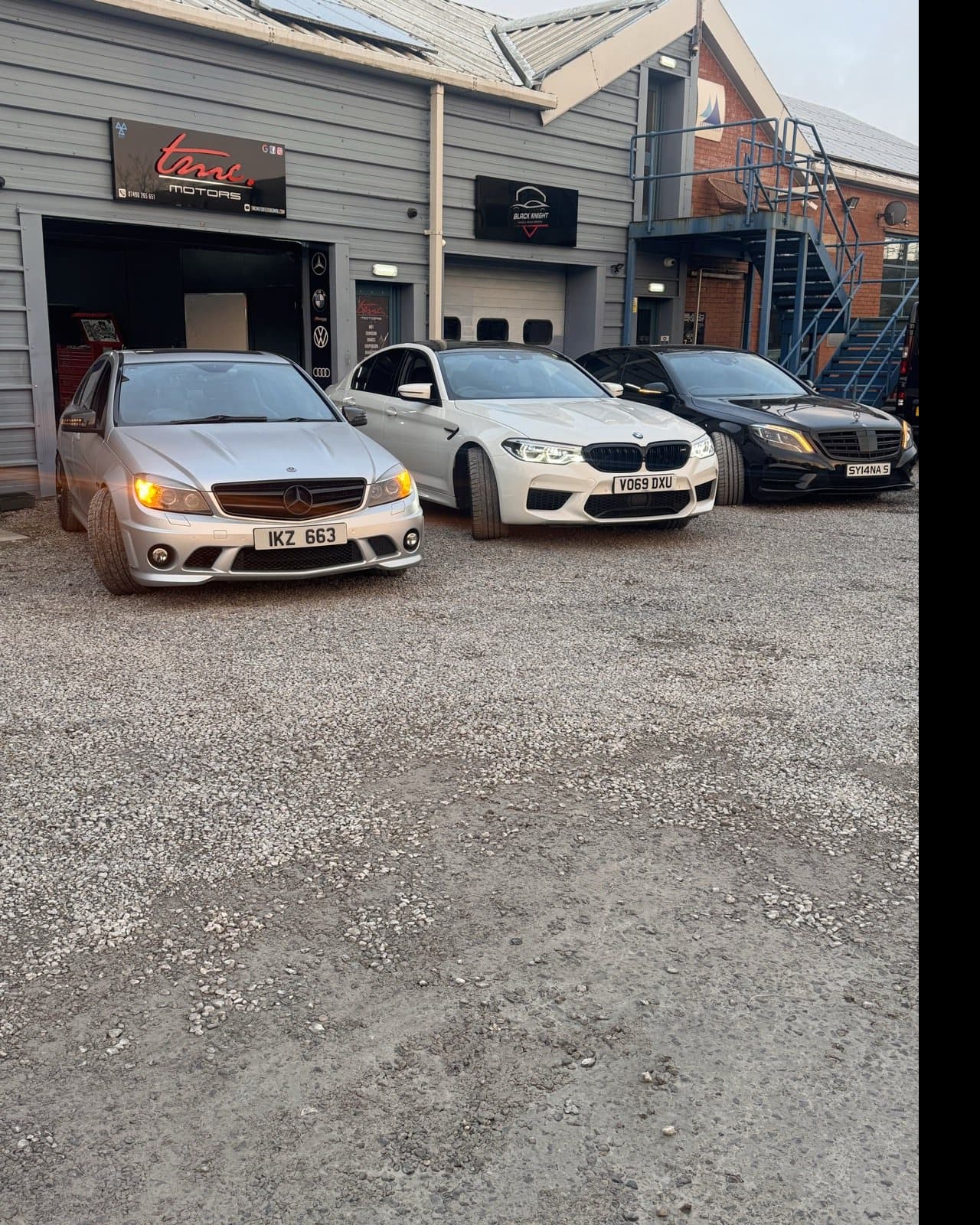 A Mercedes-AMG and two BMWs parked outside the Team Mercedes Cardiff workshop