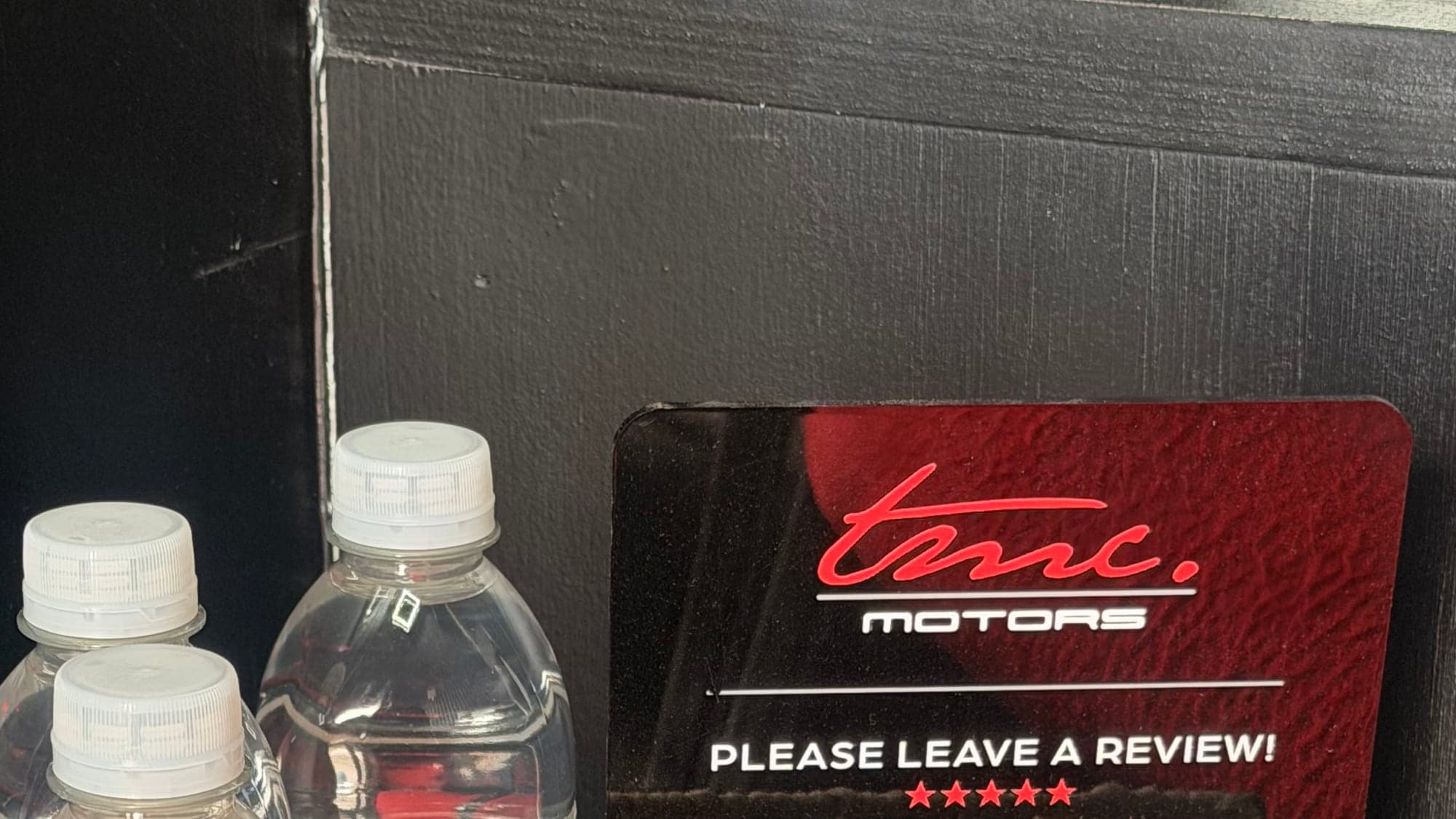 A Team Mercedes Cardiff review card on the counter, next to bottled water for waiting customers