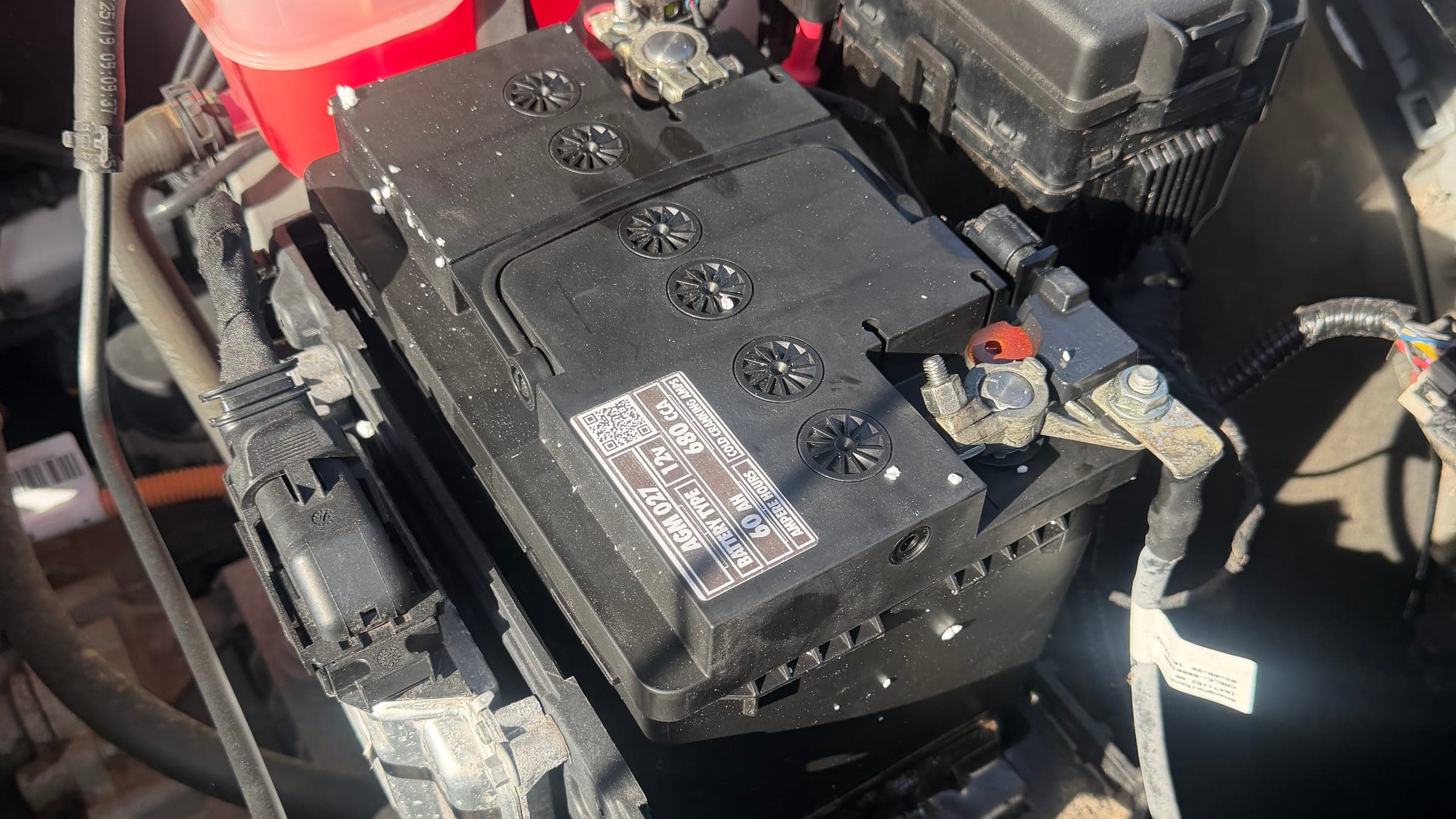 An open engine bay showing the coolant expansion tank, fuse box and battery